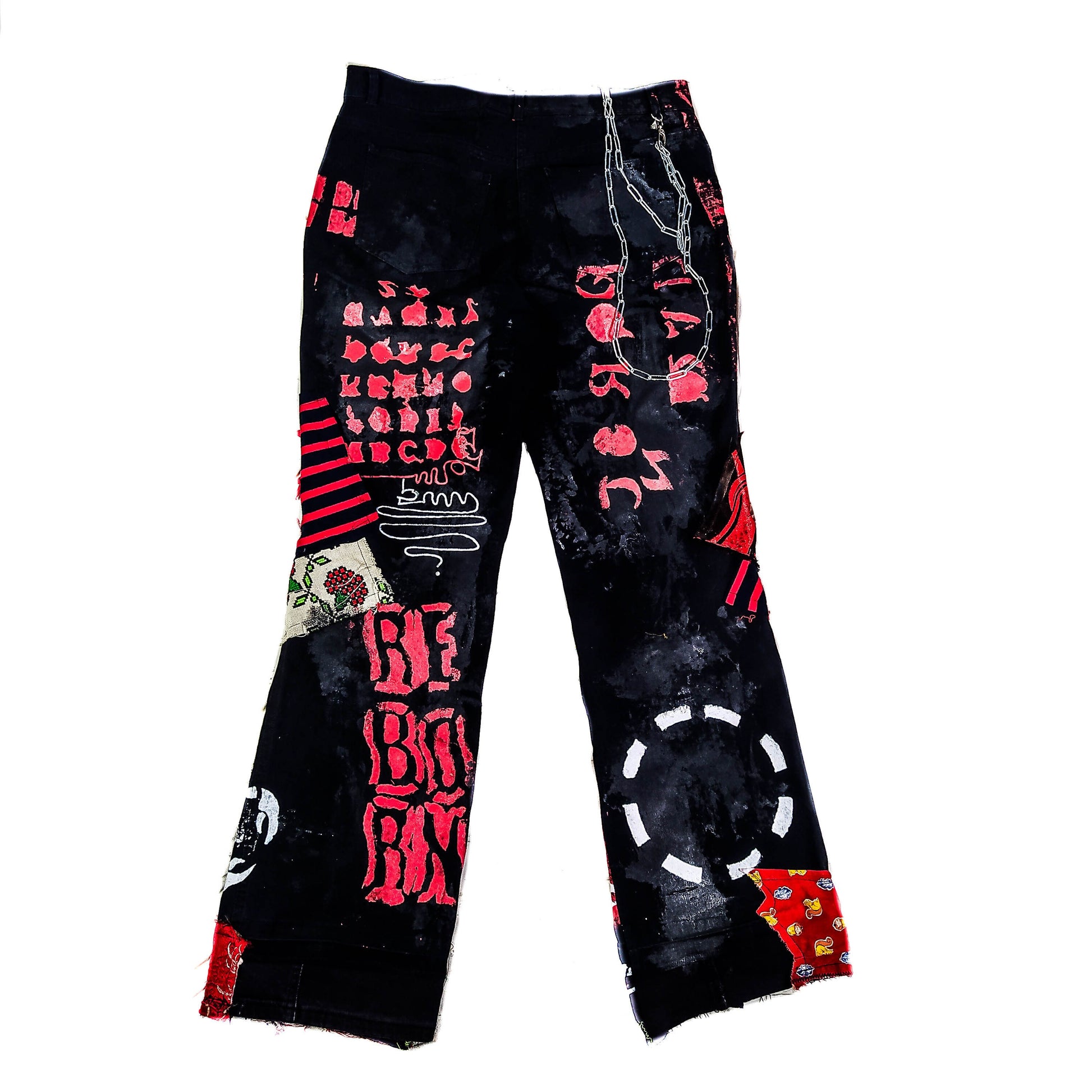 Flat laid pair of pants containing white embroideries with animes and a painted naruto, along with red patchwork, rivets, abstract paint, chains, the overall color scheme being black and red with a bit of white.