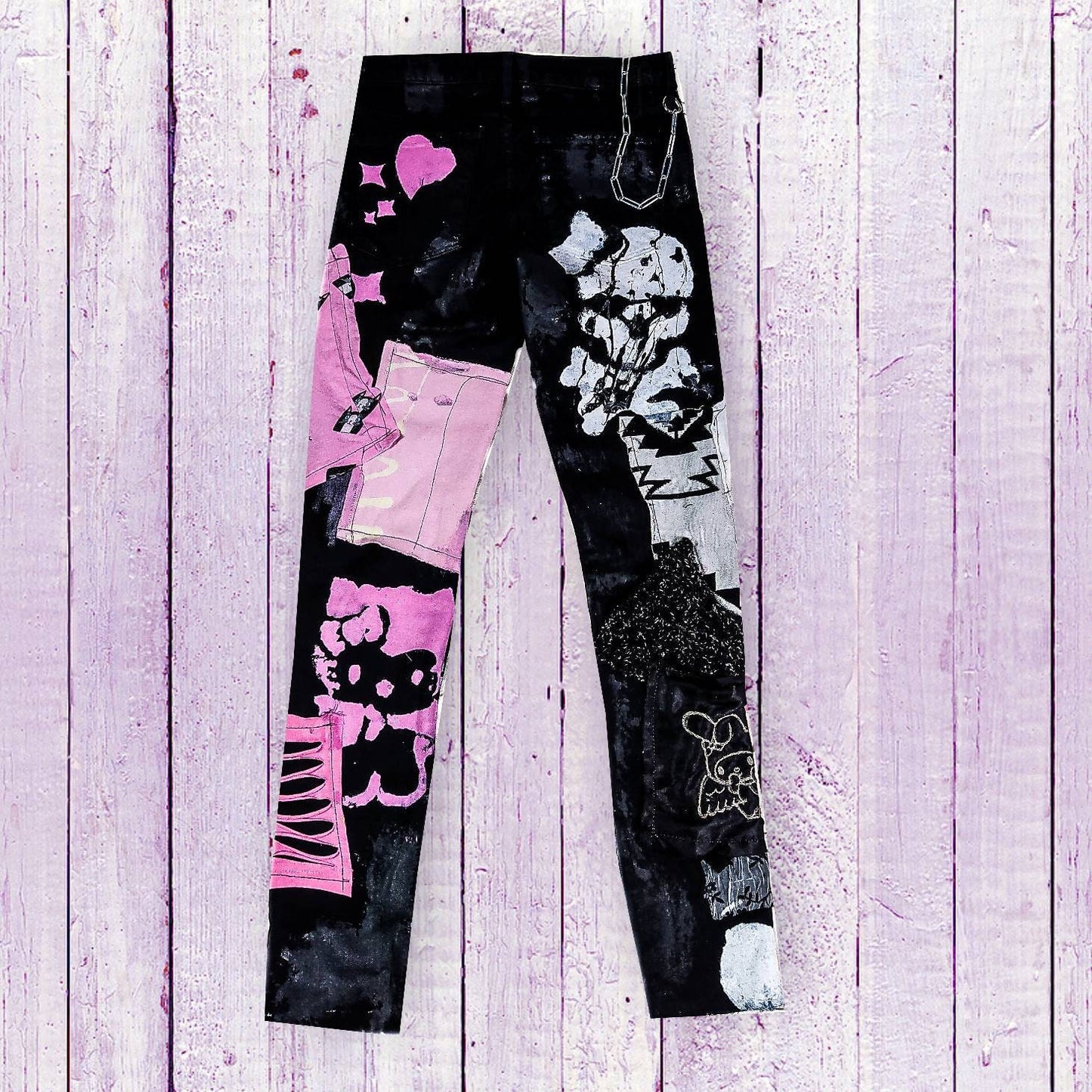 Flat laid black skinny pair with kuromy and my melody as embroidered and printed, with embroidered and painted writings such as stay sweet and make trouble, abstract pink and white patchwork, studs, rivets, painted stars and hearts, chain.