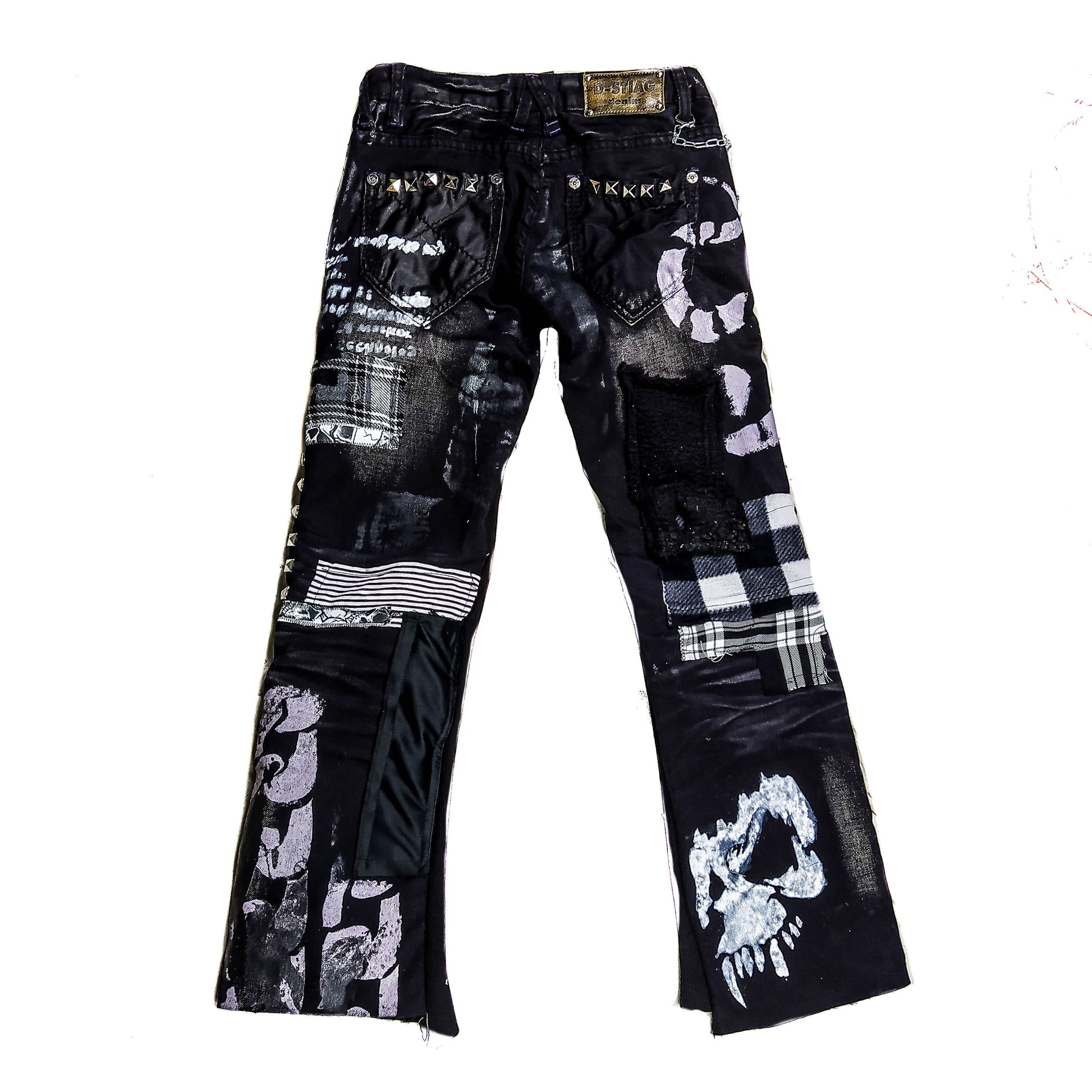 Flad laid black pair of pants with printed and embroidered skulls, eyelets, studs, chain and abstract patchwork and painting in gray, black and white.