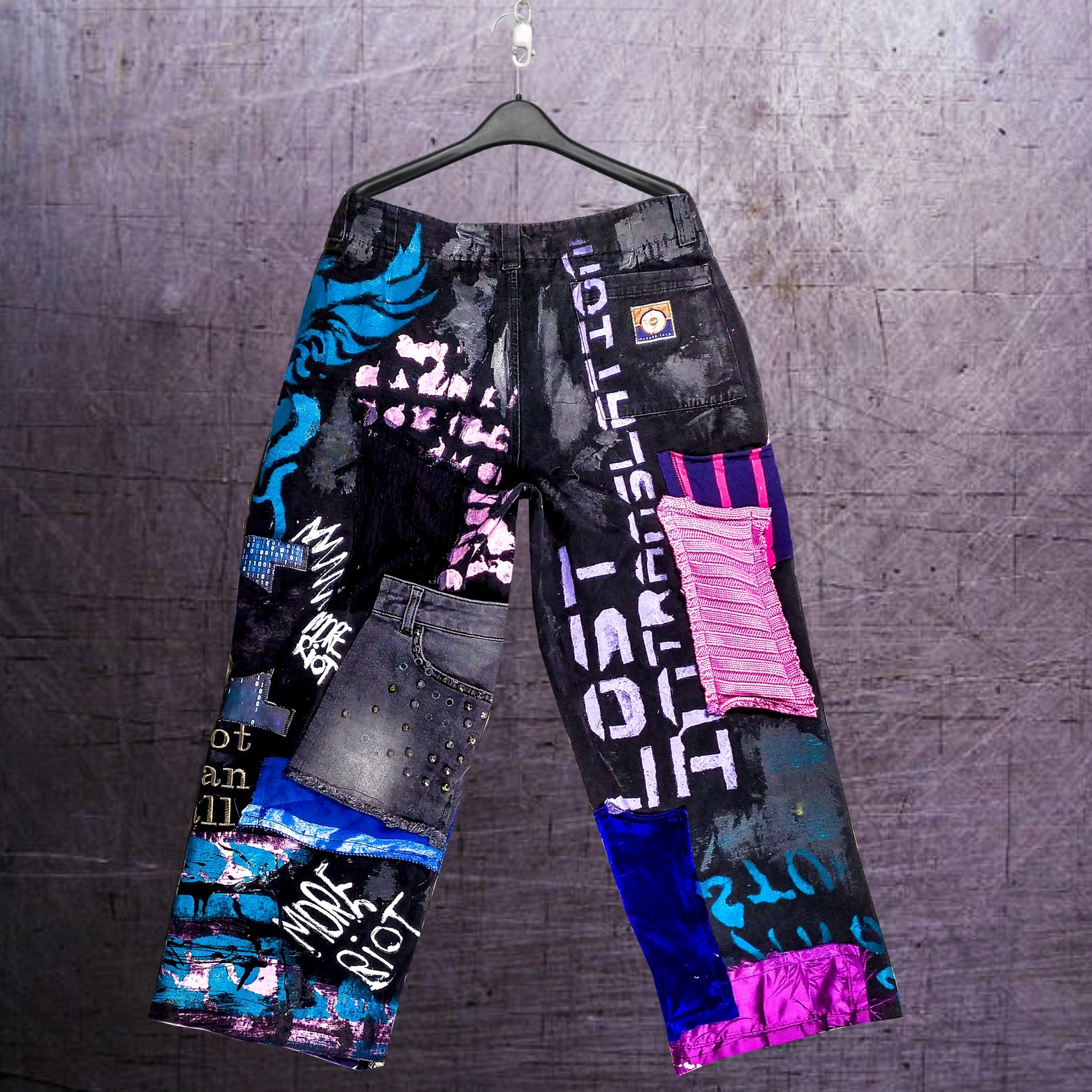 On the pair there are embroidered phrases, such as Love is to dance, Industrial symphony, Sadness is rebellion. There are also prints with chemical plants and cyberpunk themed ones. Zippers, studs, and abstract painting included.