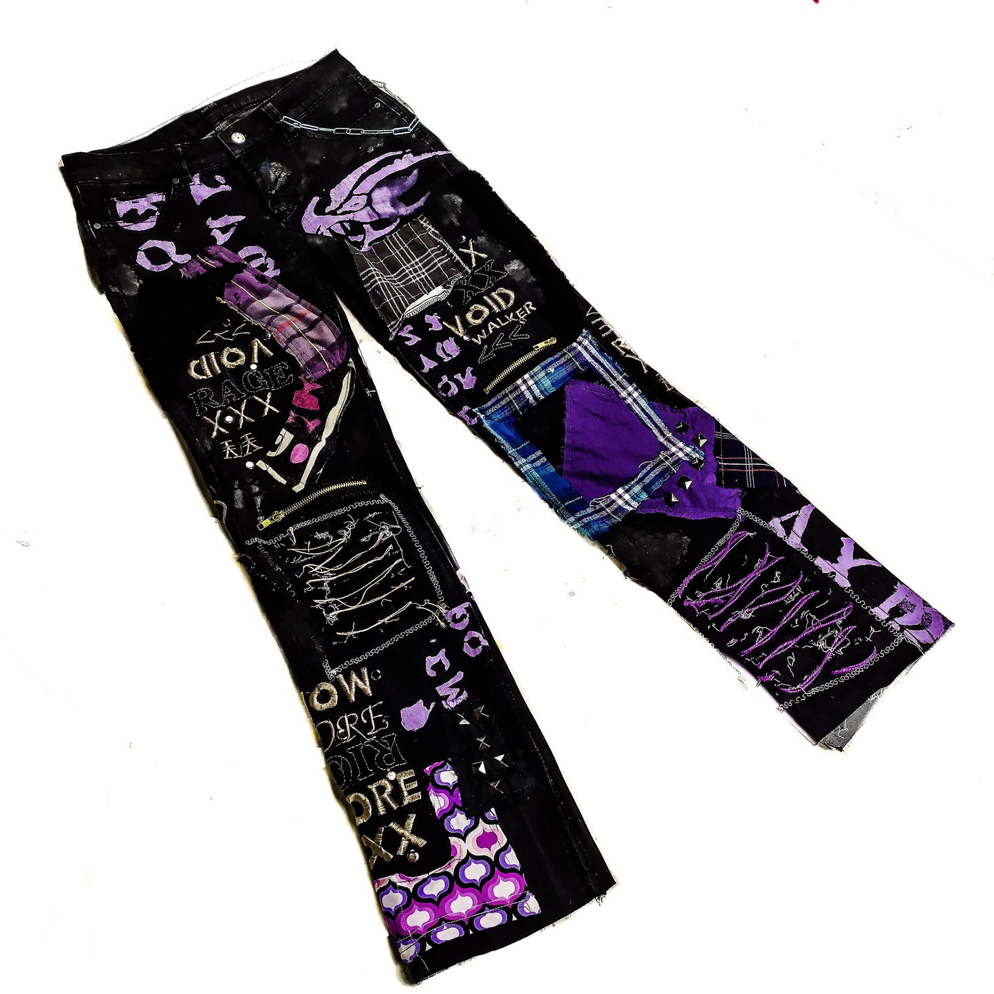 Flat laid black pair with blue and purple patchwork, embroidered words such as void walker and symbols, zippers, studs, ripped patches, chains, abstract painting.